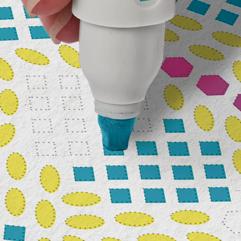 White marker with blue ink being used on a patterned paper background.