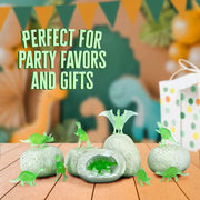Glow-in-the-dark dinosaur eggs with green dinosaur figures on wooden surface with party decorations
