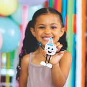 Young girl holding white Glo Pals Party Pal toy with party hat in colorful party setting