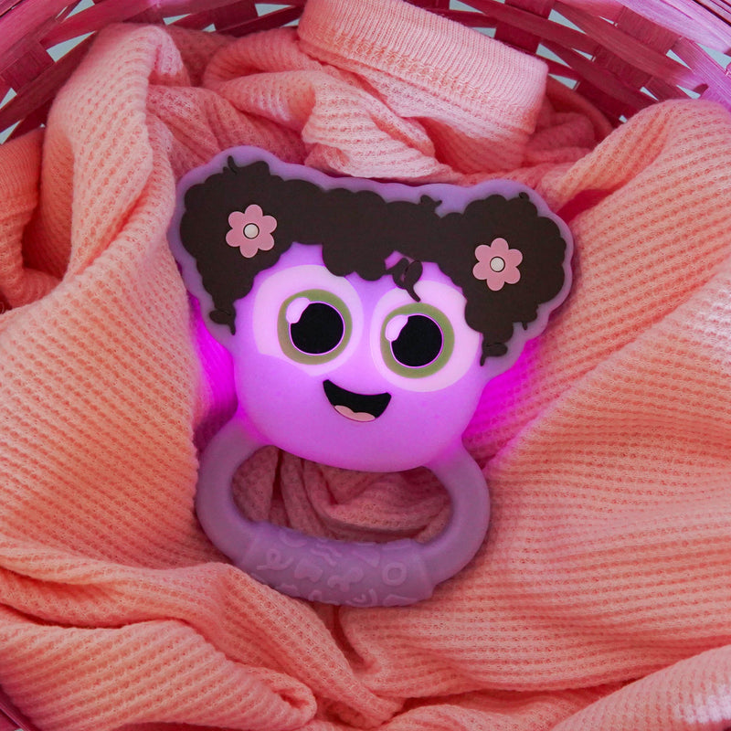 Purple Glo Pals Lumi Rattle with glowing light nestled in pink knit blanket