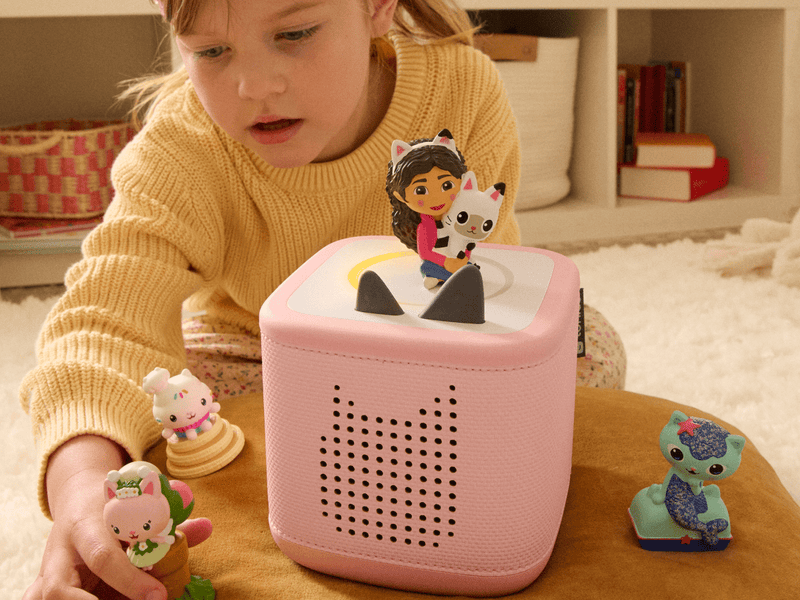 Child playing with pink Toniebox audio player and Gabby's Dollhouse Tonie figures
