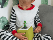 Child playing with green PJ Masks Gekko Tonie on yellow Toniebox audio player