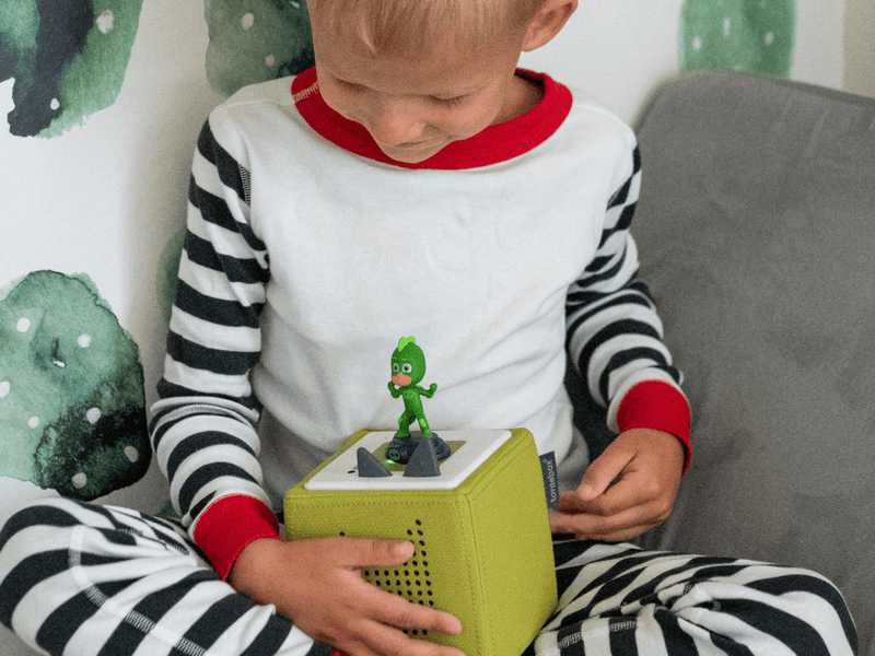 Child playing with green PJ Masks Gekko Tonie on yellow Toniebox audio player