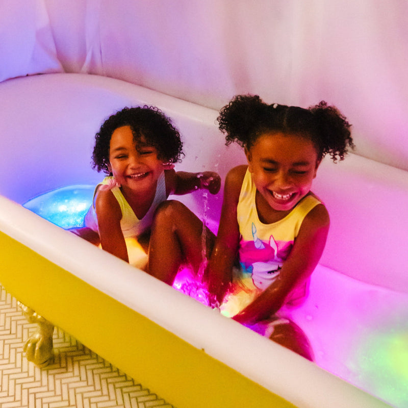 Two children playing in bathtub with colorful glowing Glo Pals light-up toys
