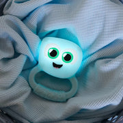 Blue cartoonish baby teether and rattle with a smiley face on a textured fabric background.