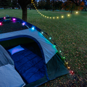 Colorful globe string lights illuminating tent at outdoor camping setup