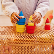 Child playing with colorful stacking gnomes on a textured surface.
