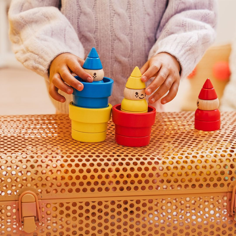 Child playing with colorful stacking gnomes on a textured surface.