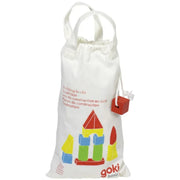 A white drawstring storage bag with handles, featuring a colorful printed illustration of toy building blocks and the 'goki basic' logo. A small red building-brick-shaped tag is attached to the side.