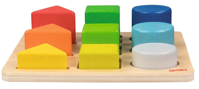 A wooden shape-sorting toy with colorful geometric blocks and cylindrical pieces on a light natural wood base. The visible brand name 'goki' appears in red on the bottom right of the base.