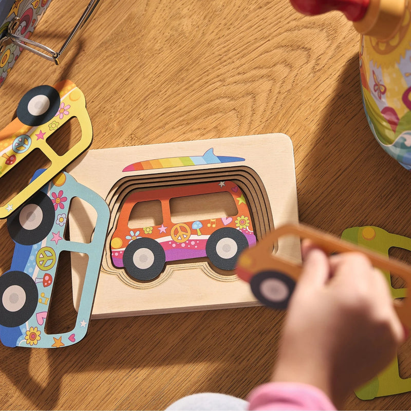 Lifestyle image of child putting Layered Puzzle of a Van togetheron a wood table background.