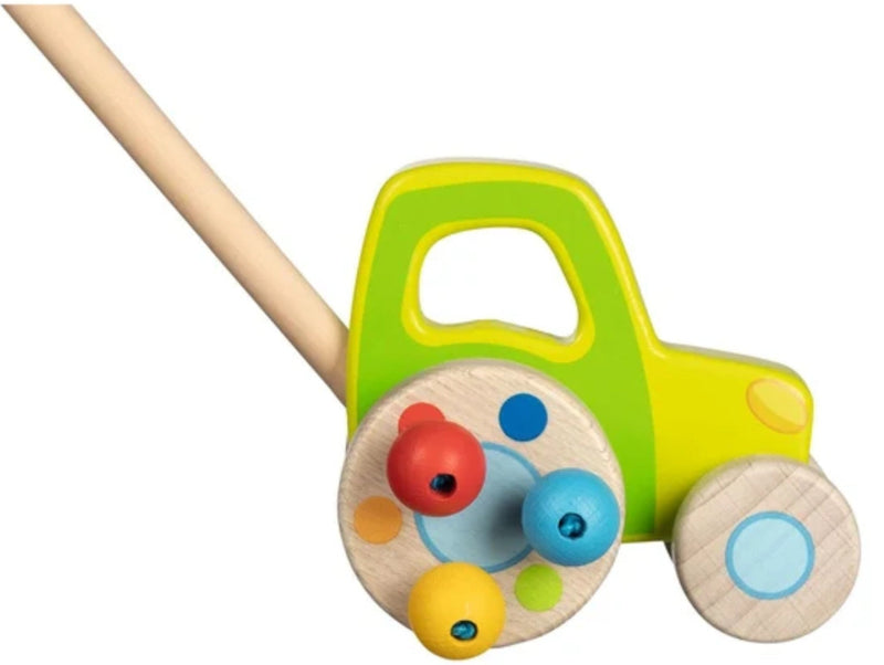 A wooden baby push toy shaped like a lime green and yellow tractor, featuring colorful spherical pegs on the front wheel and a natural wood handle on a white background.