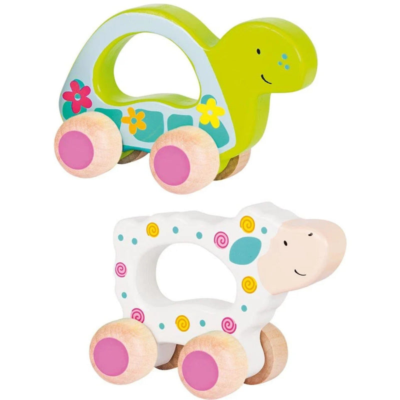 Two wooden push toys for babies: a green turtle and a white sheep, both decorated with colorful patterns and featuring pink-painted wheels, shown on a plain white background.
