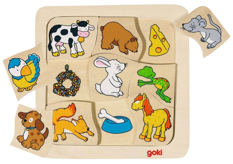 A Goki wooden animal puzzle board with multiple colorful animal and object pieces arranged on a light wood board, photographed on a white background.