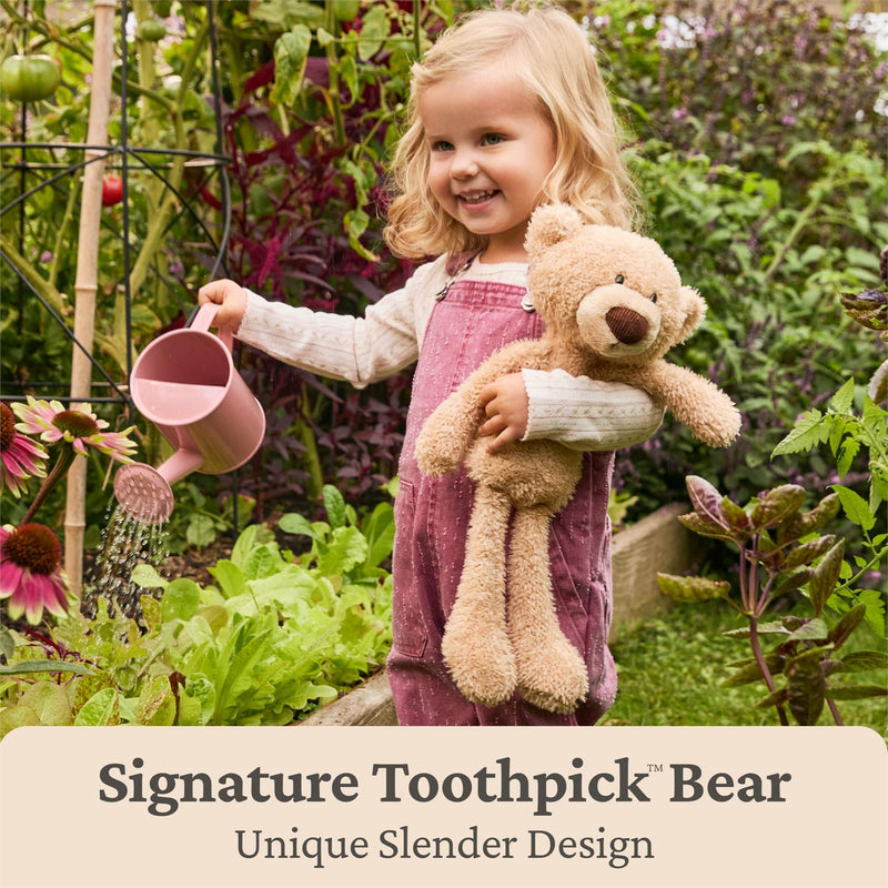 Child gardening while holding a tan GUND Forever Friends Promise Toothpick Bear plush