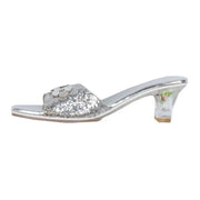 Silver sequined slip-on sandal with decorative flower detail and clear acrylic heel