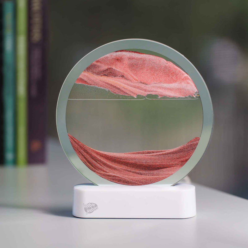 Circular LED sand art display with pink colored sand creating landscape patterns on white base