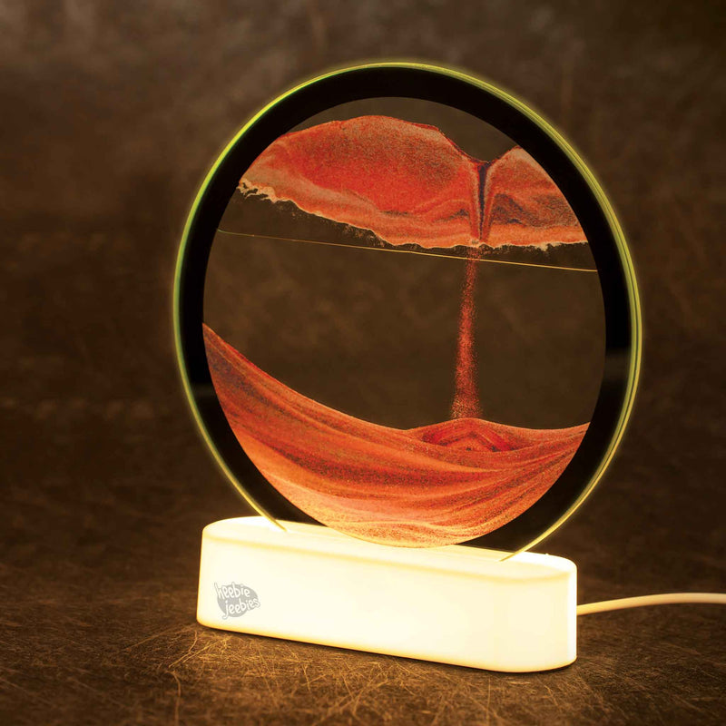 Illuminated circular sand art display with orange sand patterns on white LED base