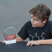 Child examining Lyells Sand Art LED display showing layered sand patterns in circular frame