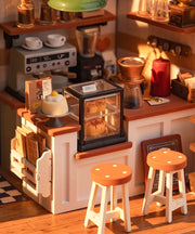 Miniature cafe dollhouse with coffee machine, display case, stools and warm lighting