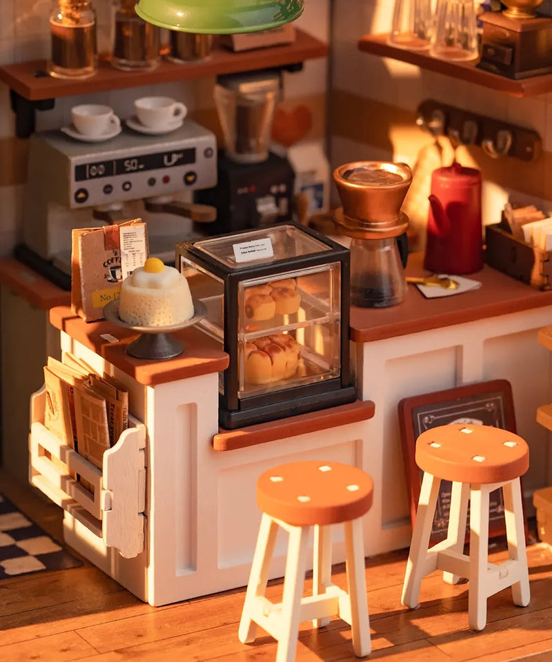 Miniature cafe dollhouse with coffee machine, display case, stools and warm lighting