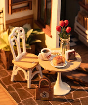 Miniature cafe scene with white table, chair, coffee cup, croissant and small decorations