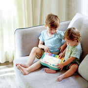 Two young children sitting on sofa playing with Hape Pixel Piano toy together