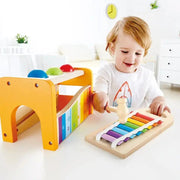 Toddler happily playing with Hape Pound and Tap Bench wooden xylophone toy