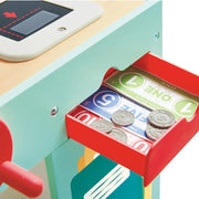 Close-up of wooden supermarket toy cash drawer with play money bills and coins
