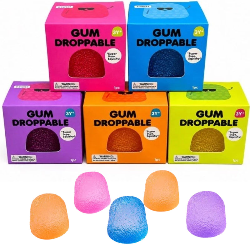 Five colorful boxes of GUM DROPPABLE squisies arranged in a pyramid on a white background. The boxes are pink, blue, purple, orange, and yellow, each showing a different colored gum through a clear window on the front.