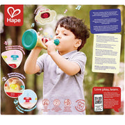 A child playing with a toy trumpet from Hape.  Picture shows product features, text callouts, and the Hape logo displayed on a colorful promotional graphic.