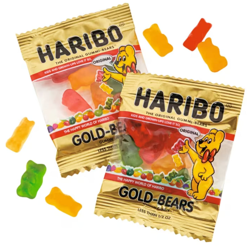 Two bags of Haribo Gold-Bears gummy bears candy on a white background, with several loose gummy bears scattered around.