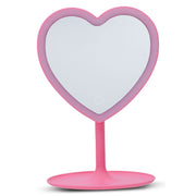 Pink heart-shaped vanity mirror with stand on white background