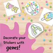 Decorate your stickers with gems! Stickers featuring cute cartoon designs including a cat, a popsicle, and a smiling face with colorful gem-like dots, arranged on a light wood background with scattered multicolored gems.