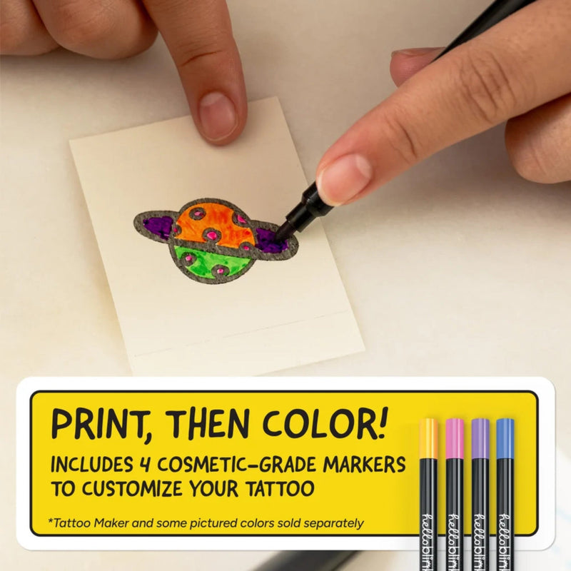 Person coloring a tattoo design on a small piece of paper with markers, accompanied by promotional text for a tattoo-making kit.