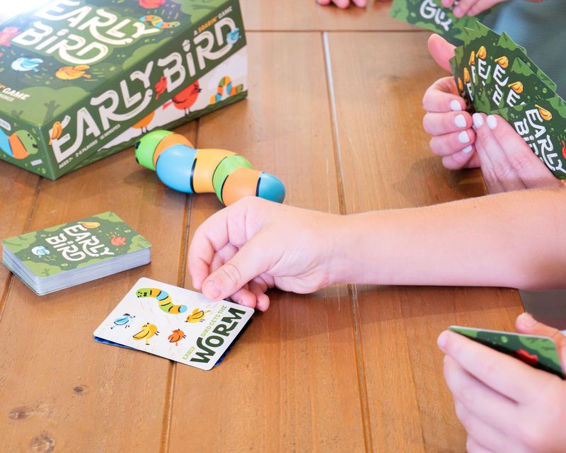 Children playing Early Bird card game by Hootenanny Games at a wooden table.
