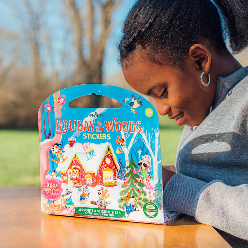 Child examining eeBoo Holiday in the Woods stickers package with festive woodland animal designs