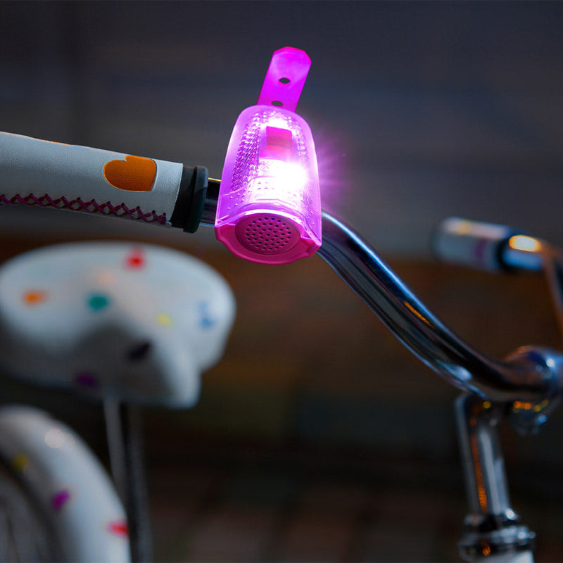 Pink illuminated bike horn light attached to bicycle handlebars in evening setting