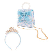 A kids accessory set on a white background, featuring a light blue tweed mini handbag with a pearl beaded handle, a light blue satin bow, a gold chain strap, a matching light blue tiara headband, and a pearl headband.