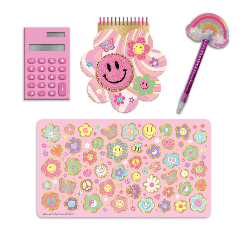 A pastel pink school or desk accessory set on a white background, including a pink calculator, a flower-shaped notepad with a smiley face, a rainbow pen, and a sheet of colorful stickers.