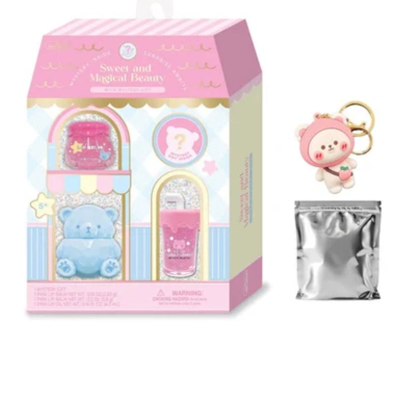A pink and cream toy beauty gift set box labeled 'Sweet and Magical Beauty' shown next to a small pink bear keychain with a gold ring and a silver foil pouch on a white background.