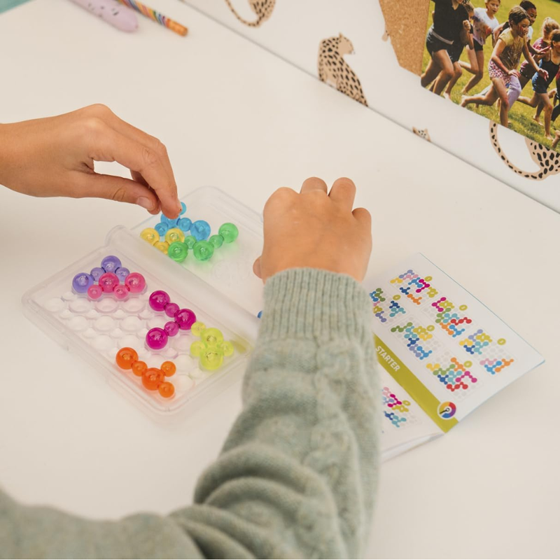 Child playing with colorful IQ Bubbles on a table with educational materials.