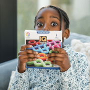 Child holding a box of IQ Noodles puzzle game. 
