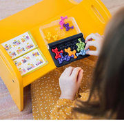 Child playing with a colorful puzzle game on a yellow table.