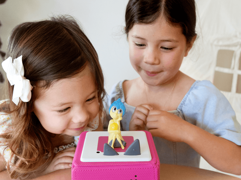Two children playing with Joy Tonie figure from Disney Inside Out on Toniebox