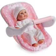 A pink and white polka dot baby doll seat with a baby doll wearing a white outfit and hat, shown on a clean white background.