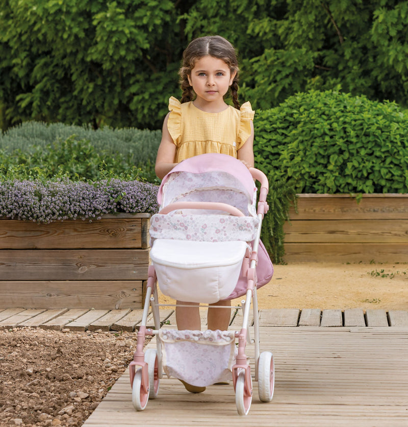 Child pushing the pink Bonbebé sports pram outdoors in a garden.