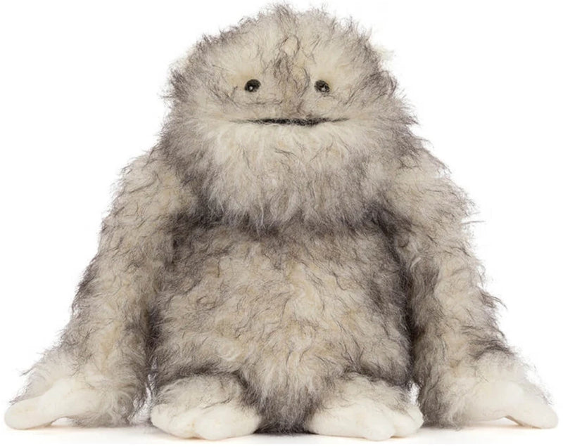 A fluffy gray and white furry monster plush toy with small black eyes and a stitched mouth, sitting against a plain white background.