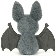 The backside of a plush toy bat with soft gray fur, large upright ears, dark wings spread wide, and a small pink nose on a plain white background.
