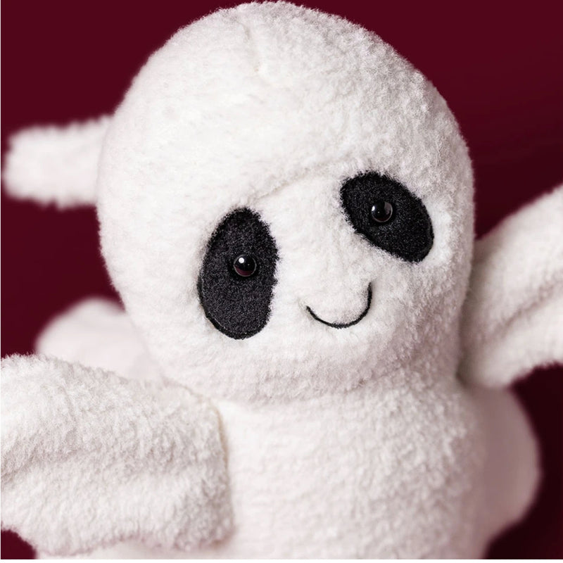 A close-up of Ghost Bob, a plush ghost toy with black embroidered eyes, nose, and mouth, set against a solid dark red background.